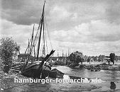 0954029 das Köhlfleet in Hamburg Finkenwerder bei Ebbe - das Fleet ist fast trocken und die Frachtschiffe, Fischkutter und Schuten liegen fest im Schlick; am gegen über liegenden Ufer stehen Weiden an der Wiese.
