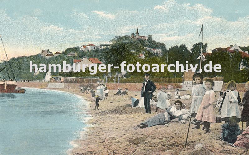 09540365 Badestrand am Elbufer von Blankenese ca. 1900; Mdchen in Kleidern stehen im Sand, andere bauen eine Sandburg. Eine Mutter liegt mit Kleid im Sand, dahinter ein Mann mit Anzug. Im Hintergrund die Huser von Blankenese und der Sllberg.