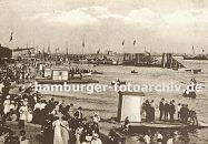 09540368 historisches Bild vom Strand an der Elbe bei Altona, Oevelgoenne. Frauen mit langen Kleidern und Hten und Mnner in Anzgen flanieren am Strand oder warten auf ein Ruderboot, das an den Verleihstationen am Elbstrand vermietet wird. Einige Ruderboote fahren auf der Elbe - im Hintergrund ein Schiffsanleger mit Ponton und Dalben. Rechts davon eine angeschrgte Konstruktion, die im Winter den Anleger vor Eisgang schtzen soll. 