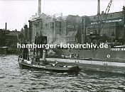 0954048 Speichergebude im Altonaer Hafen - ganz lks. eine Getreidemhle, ber lange Ladestutzen wird das Getreide von den Schiffen in das Gebude transportiert. Die Speichergebude sind in der fr die Zeit um 1900 typischen Industriearchitektur gehalten; in der Bildmitte ist das Elblagerhaus mit den Eingangsluken zu den einzelnen Lagerbden - die einzelnen Lagerbden mit den Eingangsluken werden mit Winden / Krnen die unter dem Gebudedach montiert sind,  beliefert. Auf der rechten Bildseite der Kohlehof / Kohlespeicher; der Greifer eines Krahns hat gerade eine Ladung Kohle vom Schiff geholt - aus dem Greifer rieselt links und rechts die Kohle heraus. Im Vordergrund liegt ein Schlepper am Ponton unter Dampf, dahinter Duckdalben, die aus Baumstmmen gefertigt und in den Hafenboden gerammt sind - an ihnen knnen Schiffe festmachen. 