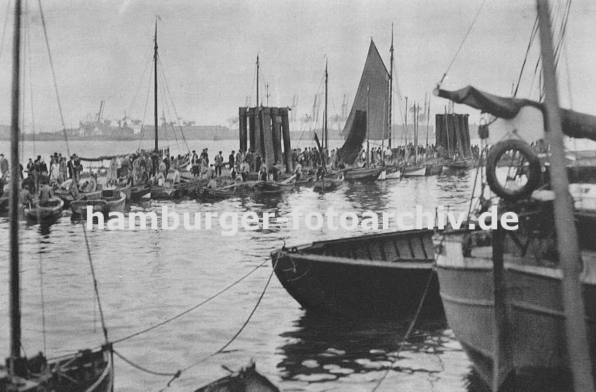 0954059 Fischmarkt in Hamburg Altona; dicht gedrngt liegen die kleinen Khne am Ponton vor der Fischauktionshalle. Die Kunden vergleichen die Ware von den Fischern. Im Hintergrund Hafenanlagen des Hamburger Hafens. 