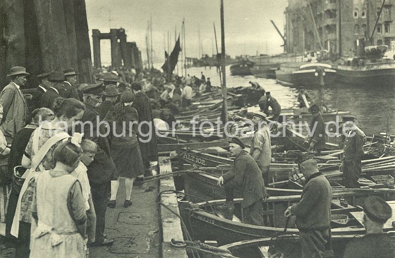 historische Fotos von Hamburg-Altona - Fischmarkt, Fischer + Fischerboote am Anleger.  016_0954060 Fischerboote haben am Ponton des Altonaer Fischmarktes angelegt. Die Fischer an Bord preisen Ihre Ware an - Die Besucher und Besucherinnen des Fischmarktes gehen an den Booten entlang und begutachten die Fische. Im Hintergrund liegen Schuten und Binnenschiffe am Altonaer Speicher. www.hamburg-bilder.biz