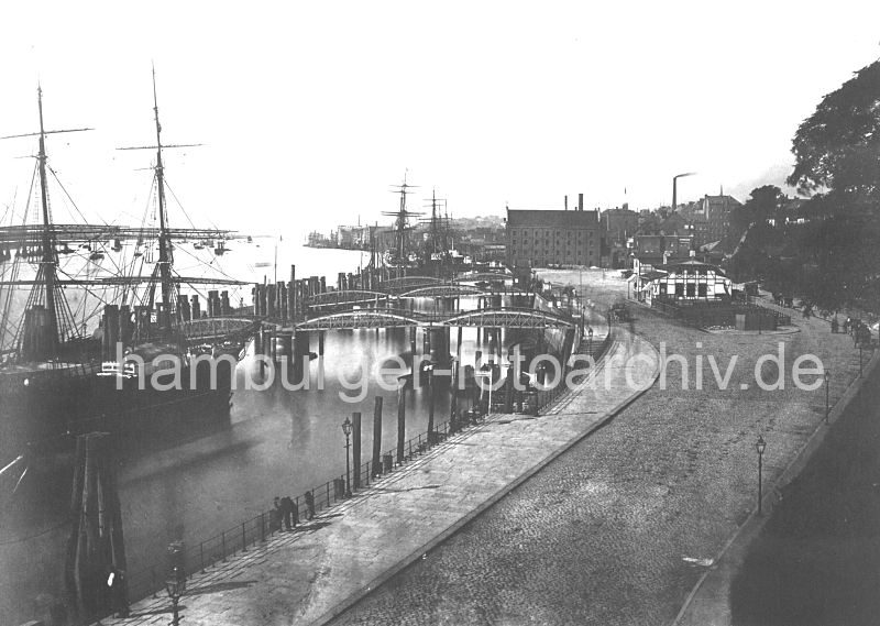 historisches Motiv von den St. Pauli Landungsbrcken - Fhrhaus, Wassertreppen, Duckdalben 0954067_30 DWassertreppen fhren zu den Anlege-Pontons der St. Pauli Landungsbrcken - die eisernen Treppen sind beweglich, so dass sie den Hhenunterschied der Tide (ca. 3,60m) ausgeglichen werden kann. An den Holzpfhlen (Duckdalben) machen die Segler im Strom fest. Rechts das St. Pauli Fhrhaus und im Hintergrund Industriearchitektur von Altona. Sie mchten dieses Motiv z.B. auf Fotoleinwand erwerben? www.hamburg- bilder.biz