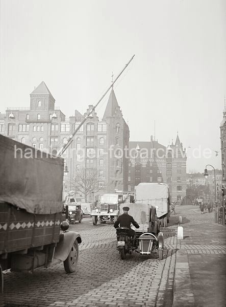 Hamburger Bilddokumente aus dem Archiv der HHLA; Lastkraftwagen am Bahnbergang Brooktor; ca. 1936. 01147752_B_333 Dichter Straenverkehr in der Speicherstadt - Lastkraftwagen, deren Ladeflche mit Planen abgedeckt sind berqueren den Bahnbergang am Brooktor. Ein Motorrad mit Beiwagen fhrt Richtung St. Annenbrcke. Im Hintergrund gehen Fugnger und ein Pferdfuhrwerk berquert die Wandbereiterbrcke.