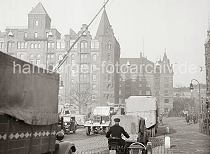 01147752_B_333 Dichter Straenverkehr in der Speicherstadt - Lastkraftwagen, deren Ladeflche mit Planen abgedeckt sind, berqueren den Bahnbergang am Brooktor. Ein Motorrad mit Beiwagen fhrt Richtung St. Annenbrcke. Im Hintergrund gehen Fugnger und ein Pferdfuhrwerk berquert die Wandbereiterbrcke.