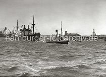 01168_B_215a Der Schlepper FAIRPLAY XIII schleppt den Motorfrachter OLBERS in den Hamburger Hafen. Im Hintergrund lks. liegt ein Schiff im Schwimmdock der Deutschen Werft am Reiherstieg. Rechts ist die Einfahrt zum Grasbrookhafen und das Sandhft zu erkennen. Dahinter der Schuppen 13 am Dalmannkai, Dcher der Speichergebude in der Speicherstadt, der Turm des Michels und das Gebude vom Kaiserspeicher am Kaiserhft.