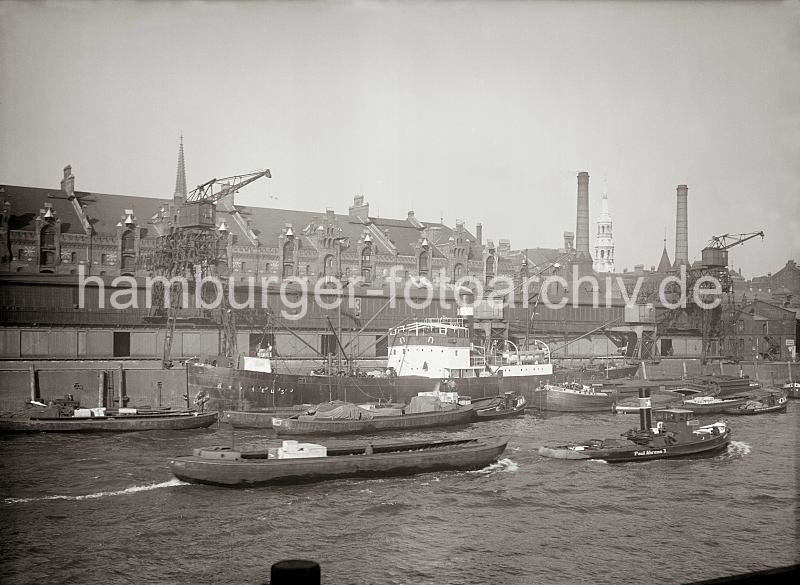 Historische Fotodokumente aus dem Archiv der HHLA Schlepper mit Schute im Sandtorhafen / Frachtschiff am Sandtorkai, Schuppen 3; alte Hamburg Bilder auf Fotoleinwand oder Posterprint. 011778_432 Der Frachter ORPHEUS liegt vor dem Schuppen 3 des Sandtorkais - Schuten und Lastkhne haben lngsseits fest gemacht.  Ein Schlepper zieht eine Schute durch das Hafenbecken; im Hintergrund die Giebel der Speicherstadt und die Kirchtrme der St. Nikolaikirche und St. Katharinenkirche. Rechts die Schornsteine des Kesselhauses am Sandtor.