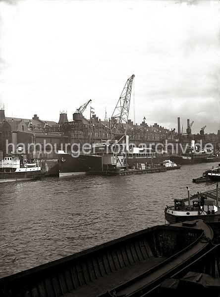 Historische Fotografien aus dem Bildarchiv der HHLA. Schwimmkran am Sandtorkai - Speicherstadt - alte Hamburg Fotografien auf Leinwand oder Posterprints. 01181_11925T Ein Schwimmkran beldt den Frachter MARYLEBONE, der am Sandtorkai mit einer groen Holzkiste. Weiter Fracht liegt im Laderaum einer Schute zum Verladen bereit. Hinter den Kaischuppen sind die Dcher der Speicherstadt zu erkennen, auf der linken Seite die beiden Schornsteine vom Kesselhaus.