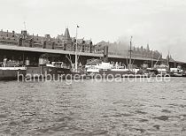 02182_618a Drei Kstenmotorschiffe haben am Sandtorkai des Sandtorhafen fest gemacht - in der Mitte der Frachter GREIF und rechts davon die MEISE. Zwischen den Schiffen ist die gelagerte Ware in den zur Wasserseite offenen Kaischuppen 2 zu erkennen. Auf den Schienen laufen die Rollkrne am Hafenkai entlang. Hinter dem Dach des Lagerschuppens sind die Giebel und Winden der Speicherblcke K und L an der Strae Am Sandtorkai zu erkennen.