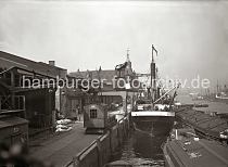 02186_86 Der Dampfer ALSTER hat am Kaiserkai fest gemacht, an seiner Seite liegen Schuten und Elbkhne. Am Halbportalkran hngt eine Hieve Kisten, die an Land gebracht und auf der Laderampe abgesetzt werden soll; im Hintergrund stehen dort Zugpferde und ein Wagen, der mit Kisten beladen ist.  Zwischen den Auslegern der Krananlagen ist der Uhrenturm des Kaispeichers A zu erkennen.