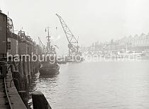 02190_720 Einer der Schwimmkrane des Hamburger Hafens arbeitet am Kaiserkai / Sandtorhafen. Eine groe Schiffsschraube hngt am Ausleger des Arbeitsschiffs. Auf dem Kai stehen die Rollkrane entlang der Schuppen auf den Gleisen. Ein Ewerfhrer stakt seine beladene Schute an die Kaimauer, um dort festzumachen.