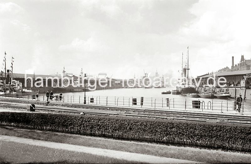 Historisches Bildmaterial aus dem Fotoarchiv der HHLA - Hafenbecken des Sandtorhafens - Kaiserkai + Sandtorkai. Hamburgbilder auf Foto-Leinwand oder Posterprints. 02196_380 Blick in den Sandtorhafen Richtung Elbe / Kaispeicher A - links der Kaiserspeicher und rechts der Sandtorkai. Eine Familie mit Kinderwagen geht auf dem Kai - ein Kind schieben sein Fahrrad.