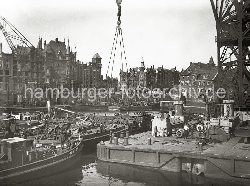 Bilder zur Geschichte des Sandtorhafens. Kriegszerstrung im Hamburger Hafen - Bergung einer Lokomotive im Sandtorhafen; ca.1948. Hafenfotos auf Foto-Leinwand und FotoPoster.  02198_1 Im Sandtorhafen wird eine Lokomotive mit einem Schwimmkran aus dem Hafenbecken geborgen. Im Hintergrund die teilweise zerstrte Speicherstadt - an der Fassade des Verwaltungsgebude der HHLA Bei St. Annen ist ein Baugerst zu erkennen.