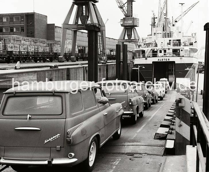 Beladung des RoRo-Frachters "Alster" - Skoda-Kombi; Sandtorhafen; ca. 1969  - historische Hafenbilder aus dem Archiv der Hamburger Hafen und Logistik AG (HHLA). alte Hamburgbilder aus dem Hafen - Prints auf Leinwand / Posterprint als Geschenk fuer buero. 02200_130 Das Roll on Roll off (RoRo) Schiff ALSTER hat seine Heckklappe geffnet - ber die Laderampe wird der Frachter mit dem SKODA Kombi Octavia beladen. Der Personenkraftwagen des tschechischen Herstellers kann mit seinem 51 Ps starken Motor eine Hchstgeschwindigkeit von 115 km/h erreichen. Vor dem Schuppen 10 des Sandtorhafens stehen mit groen Holzkisten beladene offene Gterwaggons.