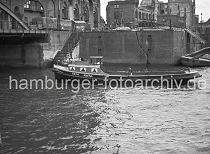 02202_0 Die Barkasse ANITA fhrt im Magdeburger Hafen Richtung Brooktorhafen; lks. ein Ausschnitt des Eisen- bogens der Magdeburger Brcke. Vor dem Kaispeicher B steht ein LKW mit Anhnger, die Ladeflche ist mit einer Plane abgedeckt. Die Kaimauer ist durch Kriegseinwirkung gerissen - auf dem Kai stehen Hausruinen; ber eine Holzrutsche werden Tmmer und Steine in die darunter liegende Schute geladen.