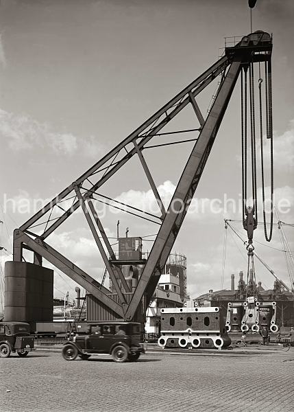 Historische Fotos aus dem Bildarchiv der HHLA; Dampfkran am Kranhft - Maschinenteile auf dem Hafenkai - FotoPrints auf Leinwand / Posterprint als Geschenk fuer buero. 02207_557 Der 1887 errichtete Dampfkran am Kranhft gehrt mit seiner Hubkraft von ca. 150 Tonnen zu den grten der Welt -  er hat eine Hhe von 30m und 10m Ausladung. Maschinenteile liegen auf der Kaianlage und sollen auf den Frachter am Kai verladen werden. Hinter den Aufbauten des Frachtschiffs sind die Industriegebude der Gasanlage auf dem Grasbrook zu erkennen.