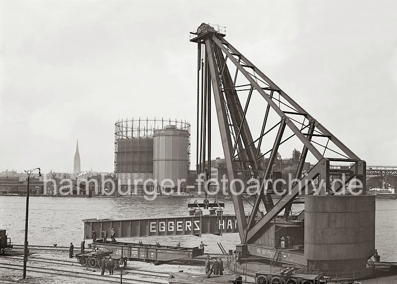 Historische Hafenbilder; Verladearbeiten am Kranhft - Blick ber die Norderelbe - FotoPrints auf Leinwand, Posterprint als Geschenk fuer Jubilaeum + GEburtstag. 02210_747 Verladearbeiten mit dem 150 t Dampfkran am Kranhft; hinter dem Gasometer und der Industrieanlage des Gaswerks ragt der Kirchturm der St. Nikolaikirche ber den Dchern der Hamburger Innenstadt heraus.