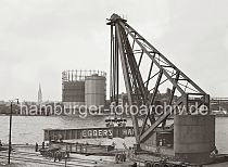 02210_747 Verladearbeiten mit dem 150 t Dampfkran am Kranhft; hinter dem Gasometer und der Industrieanlage des Gaswerks ragt der Kirchturm der St. Nikolaikirche ber den Dchern der Hamburger Innenstadt heraus.