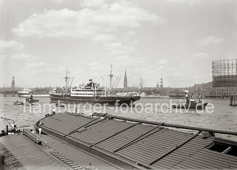 Historische Fotos von der Hansestadt Hamburg; Dampfer auf der Norderelbe - Standkai und Panorama mit Hamburger Kirchtrmen; ca. 1935 - Fotos auf Foto-Leinwand, Posterprint als Geschenk fuer Jubilaeum, Abschied + Geburtstag. 02212_603 Am Amerikakai des Segelschiffhafens liegen zwei abgedeckte Elbkhne; ein Dampfschiff wird mit Hilfe der Schlepper in das Fahrwasser der Norderelbe manvriert. Rechts das Gasometer der Gaswerke auf dem Grasbrook - hinter dem Dampfer liegen die Kaischuppen am Strandhafen. Links der Kirchturm der St. Michaeliskirche, dann die St. Nikolaikirche, der Rathausturm, die Katharinenkirche sowie die Spitze des Kirchturm von der St. Petrikirche.