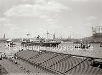 02212_603 Am Amerikakai des Segelschiffhafens liegen zwei abgedeckte Elbkhne; ein Dampfschiff wird mit Hilfe der Schlepper in das Fahrwasser der Norderelbe manvriert. Rechts das Gasometer der Gaswerke auf dem Grasbrook - hinter dem Dampfer liegen die Kaischuppen am Strandhafen. Links der Kirchturm der St. Michaeliskirche, dann die St. Nikolaikirche, der Rathausturm, die Katharinenkirche sowie die Spitze des Kirchturm von der St. Petrikirche.