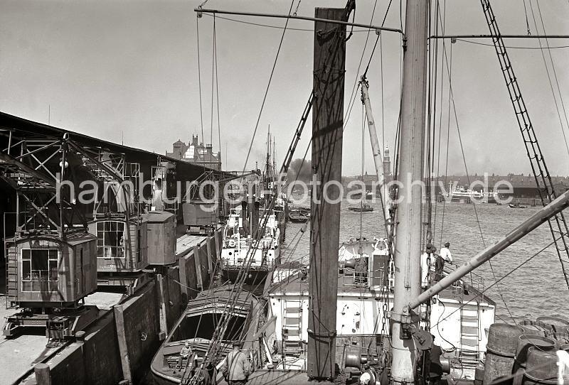 Historische Hafen Fotos aus der Hansestadt Hamburg; Frachtschiffe und Schuten im Segelschiffhafen - Rollkrne am Australiakai; ca. 1935 - Fotos auf Foto-Leinwand, Posterprint als Geschenk fuer Jubilaeum, Abschied + Geburtstag. 02216_B_225 Eine aufgedeckte Schute liegt zwischen Kaimauer und Frachtschiff - der Ewerfhrer sitzt auf einem Stapel Abdeckplanken und macht Fofftein / Pause. Er hat seine Brote ausgepackt und neben ihm steht eine Thermoskanne / Kaffeeteng. Die Rollkrne auf dem Australiakai des Hamburger Segelschiffhafens haben eine Tragfhigkeit von 3000kg.