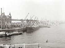 02225_694a Der Versmannkai im Baakenhafen ist dicht mit Frachtschiffen belegt. Die Krne arbeiten an der Beladung oder Lschung der Schiffe. Im Vordergrund liegt der kleine Schlepper HEDWIG unter Dampf lngsseits eines mit leeren Fruchtkisten beladene Schute. Vor dem Verwaltungsgebude mit Giebelturm stehen zweirdrige Handkarren und rechts an der Laderampe ein Pferdefuhrwerk, dessen Ladeflche hoch mit Fruchttonnen beladen ist.