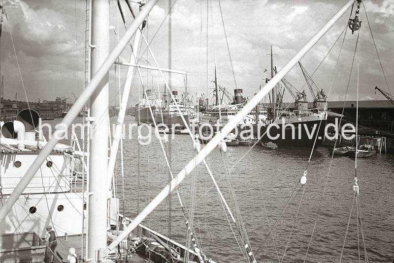 Historische Hafenmotive - Blick durch die Schiffsmasten und Ladebume in den Baakenhafen; ca. 1934. Hamburg Bilder als Poster + Fotoleinwand als Erinnerungs - Geschenk. 2227_B_251a Blick von den Schiffsaufbauten eines Frachters am Versmannkai in den Baakenhafen - am gegenber liegenden Petersenkai haben mehrere Dampfschiffe fest gemacht; beladene Schuten liegen lngsseits.