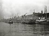 02230_190 Ein Schlepper mit hohem Schornstein schleppt eine Schute durch das Hafenbecken des Baakenhafens; weitere Schuten und Binnenschiffe liegen vor den Fruchtschuppen am Versmannkai. Rechts ein Ausschnitt des offenen Kaischuppens 25, der am  stlichen Ende des Baakenhafens liegt.