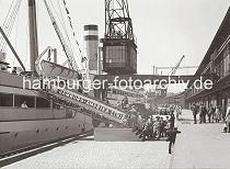 02246_759 Am Versmannkai besteigen Passagiere die Gangway eines Passagierschiffs der Hamburg-Amerika-Linie HAPAG. Unter dem Halbportalkran stehen die LKW mit dem Gepck der Amerikareisenden, ein Arbeiter wartet darauf, die Koffer an Bord des Dampfers tragen zu knnen. Auf der Laderampe stehen Kaiarbeiter des Fruchtschuppens und beobachten das Geschehen. 