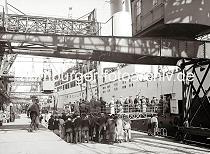 02248_756_4 Schiffspassagiere drngen sich auf dem Versmannkai vor der Gangway, um an Bord der MONTE SERVANTES zu gehen. Das 150  lange Passagierschiff konnte knapp 2500 Passagiere an Bord nehmen. Im Hintergrund werden die Koffer der Reisenden von einem Lastwagen auf dei Laderampe des Fruchtschuppens geladen.