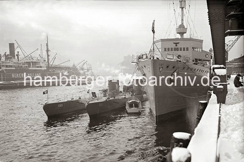 Kriegsschiffe im Hamburger Hafen - U-Boote und U-Bootbegleitschiff am Versmannkai; ca. 1938.  02249_B_334 U-Boote und ein U-Boot Begleitschiff haben am Versmannkai im Hamburger Baakenhafen fest gemacht. Hoher Schnee liegt auf der Kaianlage - ein Kaiarbeiter schaufelt unter dem Portal eines Halbportalkrans die Kaiflche frei.