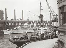 02251_767 Im Vordergrund rechts das Verwaltungs-Ziegelgebude der Fruchtschuppen im Baakenhafen. Am vorderen Kai des Magdeburger Hafens liegt ein kleines Kstenmotorschiff das auf seinem Deck Fsser geladen hat. Am gegenber liegenden Kai vor dem Kaischuppen D liegt ein Marinetransporter und dahinter sind die Schornsteine und Gasometer der Gasanstalt auf dem Groen Grasbrook zu sehen.