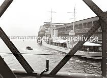 02252_768 Blick durch die Eisentrger der Baakenbrcke auf den Magdeburger Hafen mit dem Fruchtschuppen C. Ein Marine Transportschiff hat am Kai fest gemacht. Ein Teil der Besatzung sitzt unter dem Sonnensegel am Heck des Schiffes - Besucher besteigen das Schiff ber die Gangway. Im Hintergrund das gegenber liegende Ufer der Norderelbe.