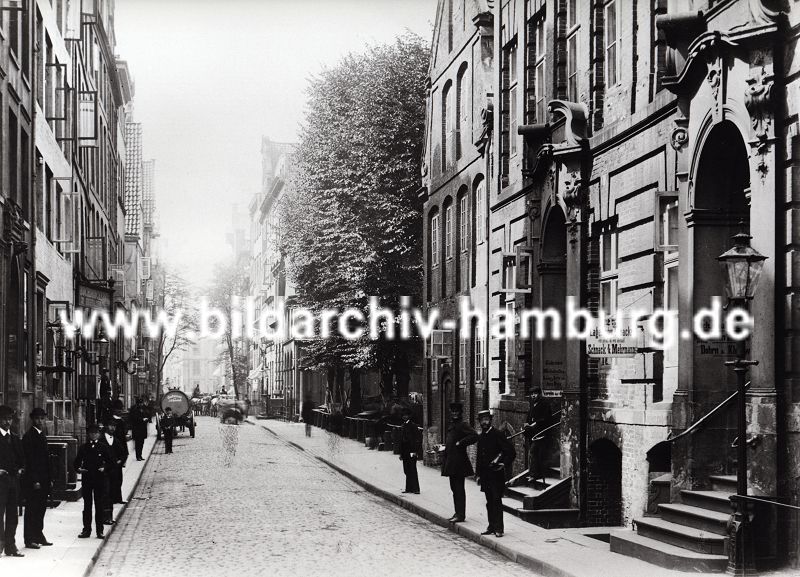 01147707 Hamburg Fotografie - Blick in den alten Wandrahm kurz bevor die Abrissarbeiten fr den Bau der Hamburger Speicherstadt beginnen. Die Huser haben prchtig dekorierte Barock - Eingnge, Strassenlaternen sind an der Hausfassade angebracht oder stehen am Strassenrand - Pferdewagen transportieren Waren an ihren Bestimmungsort, ein grosser Tankwagen mit frischem Quellwasser ist als grosse Tonne auf einem Pferdewagen montiert. Ein Firmenschild weist auf ein Tabaklager hin.  Durch den Zollanschluss Hamburgs 1888 an Preuen entstand der Hamburger Freihafen - ca. 20 000 Menschen, die auf den Elbinseln Kehrwieder, Brook und  Wandrahm lebten mussten sich eine neue Bleibe suchen - die Wohn- und Lagerhuser wurden abgerissen und die  Speicherstadt errichtet. 