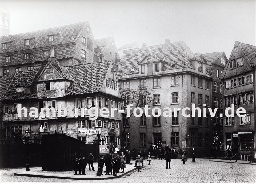 01147709 historische Hamburgbilder ::: Strassenkreuzung im Bereich Pickhuben - die historischen Huser stehen dicht gedrngt in dem zuknftigen Areal der Hamburger Speicherstadt. Ein Ladenschild links weist auf eine Barbier Stube hin sowie auf einen Klempner und Mechaniker - rechts gibt es einen Gewrzhandel und dahinter hat ein Geschft mit Haushaltswaren Tpfe an der Hauswand neben dem Schaufenster hngen. Durch den Zollanschluss Hamburgs 1888 an Preuen entstand der Hamburger Freihafen - ca. 20 000 Menschen, die auf den Elbinseln Kehrwieder, Brook und  Wandrahm lebten wurden zwangsumgesiedelt, die Wohn- und Lagerhuser wurden fr den Bau der Speicherstadt abgerissen. 