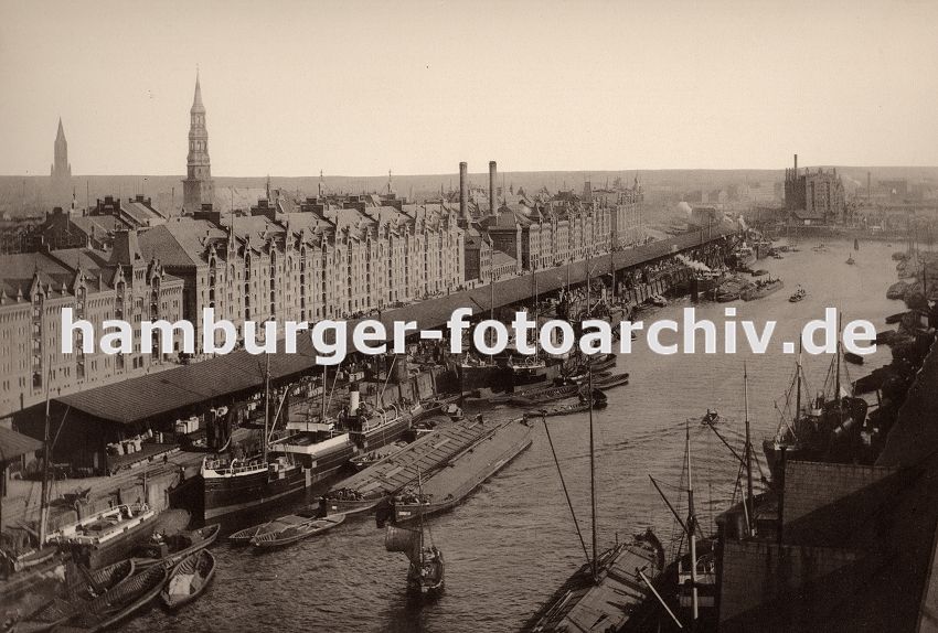 01147722 historisches Hamburg Foto : Blick vom Kaispeicher A ber den Sandtorhafen zur Hamburger Speicherstadt - dicht gedrngt liegen die Schiffe am Sandthorkai - die Frachter werden entladen, Schuten und Binnenschiffe bernehmen die Ladung und transportieren sie weiter. In der Bildmitte ragen die Schornsteine vom Kesselhaus aus der Architektur der Speichergebude heraus - dort wurde die Energie fr den Arbeitsablauf des Freihafenareals gewonnen. In der rechten Bildmitte der Kaispeicher B am Brooktorhafen. Links die Kirchtrme der St. Katharinen Kirche und der St. Jacobikirche.