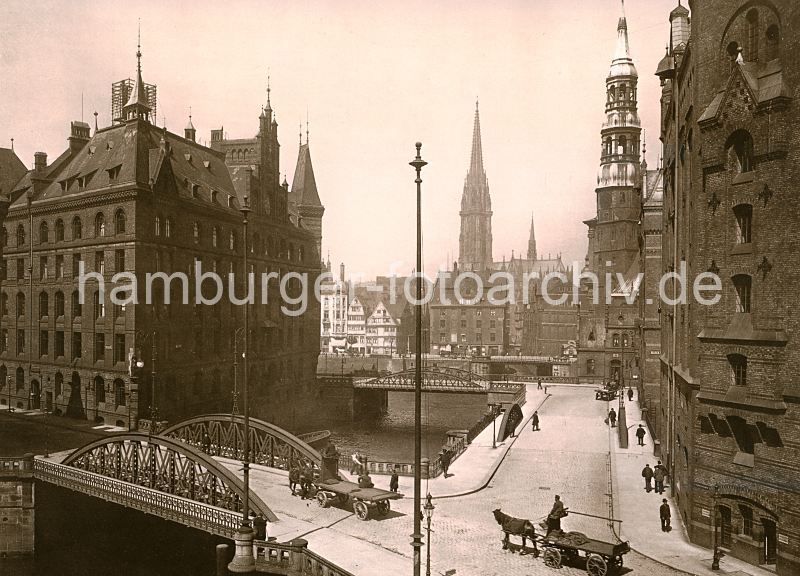 011477270  Blick ber den Kannengiesserort in der Speicherstadt Hamburg - Pferdefuhrwerke fahren in den Pickhuben ein. Links der 1888 erbaute Speicherblock H, rechts ein Ausschnitt vom Lagerhaus Q. Im Hintergrund die Kirchtrme der St. Katharinenkriche und der St. Nikolaikirche. Vor der Katharinenkirche befindet sich die Einfahrt zum Steckelhrnfleet, lks. Gebude an der Strasse " Bei den Mhren." Sie mchten das Motiv kaufen? www.hamburg- bilder.bi