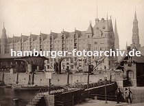 01147726 im Vordergrund die Schleuse, die den Sandtorhafen und Brooktorhafen trennt - ein Kahn liegt an der Kaimauer. Seine Ladung besteht aus Holzfssern - vor dem Speichergebude am Sandtorkai liegt eine grosse Anzahl dieser Fsser und warten auf den Abtransport. Drei unterschiedliche Krne, die auf Schienen bewegt werden, stehen am Kai. 