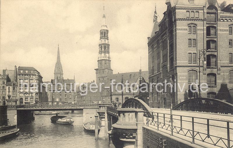 011477300 Brcken in der Hamburger Speicherstadt - rechts die Kannengiesserortbrcke mit einem eisernen Laternenmast. Dahinter der Speicherblock P - einige der Bodentren sind geffnet. Unter der gegenberliegenden Kannengiesserbrcke fhrt gerade ein Lastkahn in den Zollkanal ein. An dem gegenber liegenden Ufer ist die Mndung vom Steckelhrnfleet zu erkennen. Rechts die St. Katharinenkirchen und lks. der Turm der St. Nikolaikirche.  Sie mchten das Motiv kaufen? www.hamburg- bilder.biz