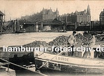 01147743 Blick vom Bauwall Richtung Niederbaumbrcke - Schiffer legen mit ihren Schuten an; mit langen Bootshaken ziehen sie ihre  Boote lngsseits - einer der Khne ist hoch mit Kohlen beladen. Rechts das Gebude der Freihafen-Polizeiwache, dahinter erstrecken sich die Speicher der Hamburger Speicherstadt.