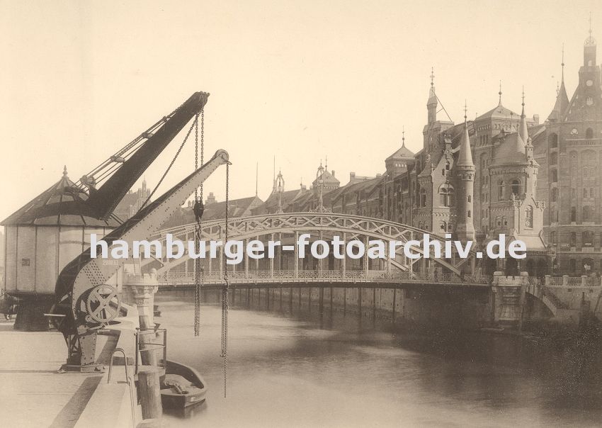 01147748 historische Fotografie Hamburgs : Blick zur Brooksbrcke, die ber den Zollkanal zum Hamburger Freihafengelnde und der Speicherstadt fhrt. An den Kaimauern des Kanals an der Strasse "Bei dem Neuen Krahn" stehen zwei Krne die die Ladung von den Schiffen an Land hieven. Die Zollstation auf der Brcke ist mit Trmen versehen, die in der Architektur der Neogotik gehalten wurden, wie auch viele architektonische Gestaltungselemente der gesamten Speicherstadt. 