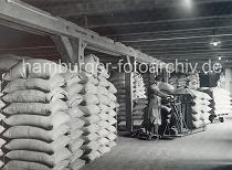 311_506a Scke mit Kaffeebohnen sind auf einem Speicherboden im Kaispeicher A / Kaiserspeicher gelagert. Lagerarbeiter wiegen Kaffeescke mit einer transportablen Waage - die nicht genutzten Gewichte stehen auf einem kleinen Wagen mit Rdern und knnen so auch mit zu dem nchsten Wiegevorgang gezogen werden.