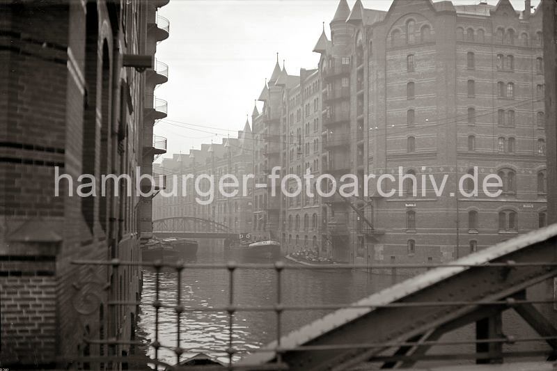 Alte Bilder Speicherstadt Hamburg aus dem Bildarchiv der Hamburger Hafen und Logistik AG HHLA. Brooksfleet - Neuerwegsbrcke, Speicherblock H - Architektur Hamburgs; ca. 1938. 507_07_B_340 Blick von der Neuerwegsbrcke auf das Brooksfleet - Schuten liegen an den Lagergebuden der Speicherstadt. ber einem Binnenschiff hngt eine Ladung Scke am Haken der Winde, die sich unter dem Dach der Lagerbden befindet. Rechts der Speicherblock H, der auch als"Sandthorquai-Hof" bezeichnet wird, dahinter die Speicher G + F; links beginnt das Speichergebude Q.
