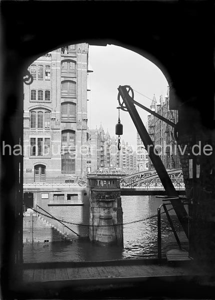 Historische Fotos Speicherstadt Hamburg aus dem Bildarchiv der HHLA. Wandkran an der Bodenluke; ca. 1934. 507_10_568 Blick vom Speichergebude H auf die Kannengiesser- ortbrcke und die dahinter liegenden Speicher am Wandrahmsfleet. Mit dem Wandkran konnte die Ware vom Lagerboden auf die Schiffe geladen werden ohne dass die Winden unter dem Dach des Backsteingebudes in Anspruch genommen werden mussten.