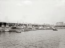 603_11_678a Blick ber das Hafenbecken des Grasbrookhafens zum Dalmannkai; u.a. haben dort die Frachter PROCRIS und CITY OF BREMEN fest gemacht. Binnenschiffe und Schuten liegen lngsseits, der Schlepper GRETE zieht einen Lastkahn an seine Position. Vor den Lagerschuppen 14 + 15 fahren Hafenkrane auf Schienen. Im Hintergrund ist links die Fassade und der hohe Schornstein des Kaispeichers B zu erkennen, gefolgt von den Gebuden des Amts fr Strom- und Hafenbau und rechts das 1928 nach dem Entwurf des Oberbaudirektors Fritz Schumacher errichtete Khlhaus.