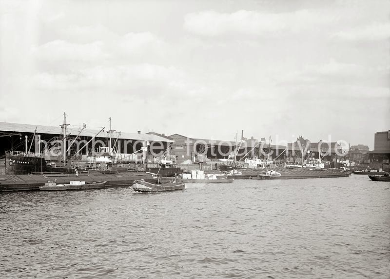 Hafenbilder von der Hansestadt Hamburg - Fotoarchiv der HHLA. Frachtschiffe und Binnenschiffe im Grasbrookhafen.  603_12_679a Blick zum Dalmannkai des Grasbrookhafens, der 1881 parallel zum Sandtorhafen fertig gestellt wurde. Die Ladung der Frachtschiffe wird ber die Hafenkrane gelscht oder die Frachter werden neu beladen. Auf der Wasserseite der Schiffe haben Binnenschiffe und Schuten fest gemacht - sie sind teilweise hoch mit Kisten beladen.